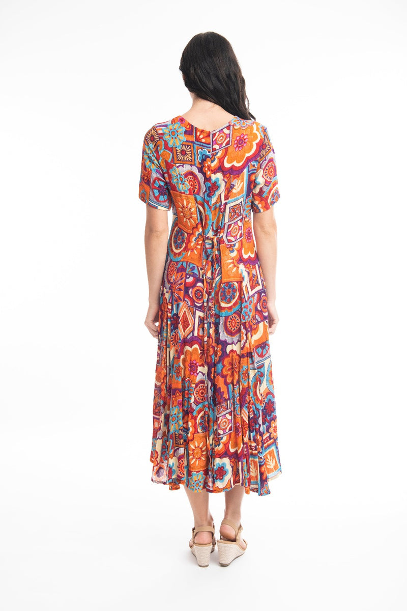 The Pissouri Godet Dress from Orientique has a v-neckline & short sleeves. It has godets to add fullness to the skirt & is a flattering calf length. It has a string tie & looks which can be tied at the back or at the front.