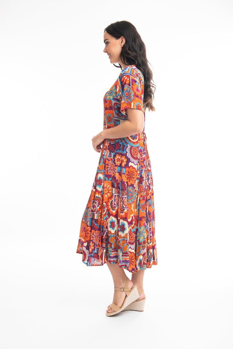 The Pissouri Godet Dress from Orientique has a v-neckline & short sleeves. It has godets to add fullness to the skirt & is a flattering calf length. It has a string tie & looks which can be tied at the back or at the front.